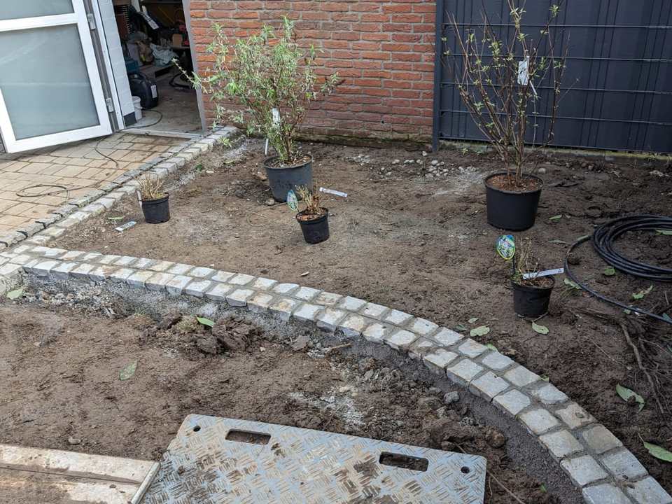 Geschwungene Pflanzbeete mit Natursteinpflaster und neuer Bepflanzung