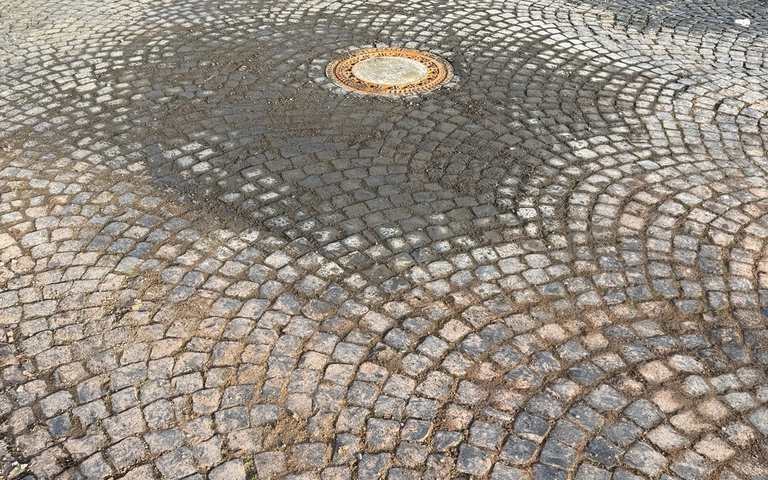 Fertig sanierte Pflasterfläche mit Schachtdeckel nahe der Universität Kassel für Kassel Wasser