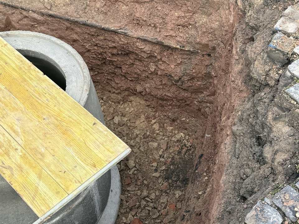 Freigelegte Baugrube mit neuem Schachtbauwerk und aufgenommenem Natursteinpflaster in Kassel