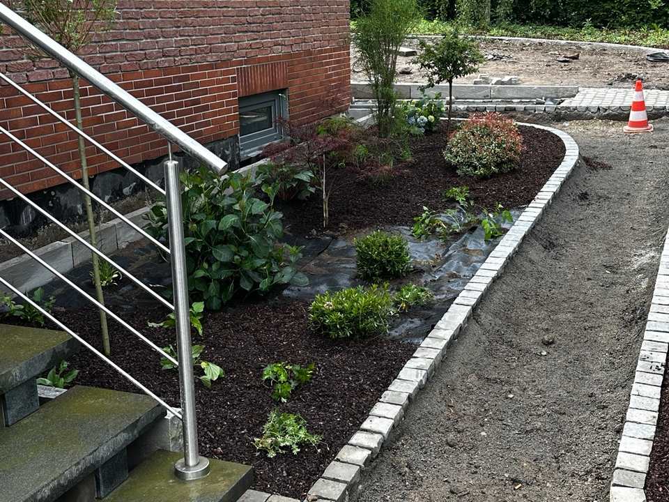 Pflasterarbeiten an einem Gartenweg mit Natursteineinfassung