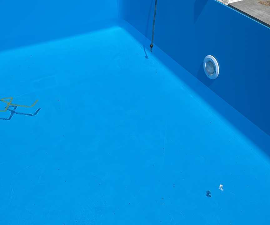 Blau ausgekleidetes Poolbecken während des Ausbaus mit Einbauteilen und Beckenrandplatten