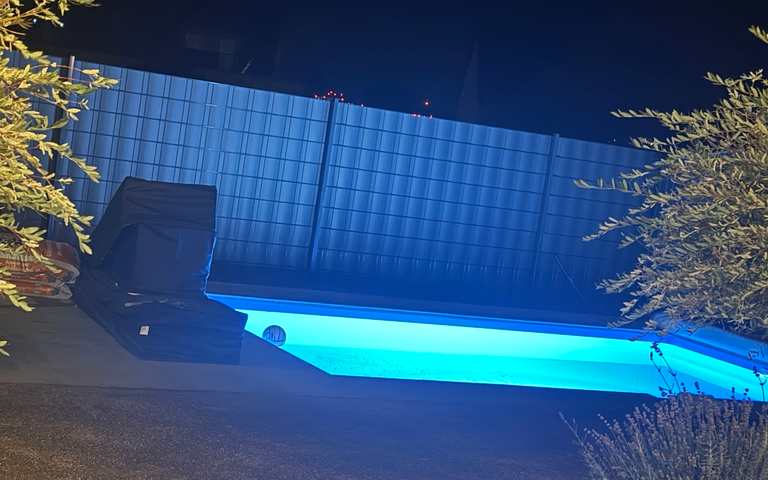 Fertiggestellter und beleuchteter Pool mit gepflasterter Umrandung in Calden bei Nacht