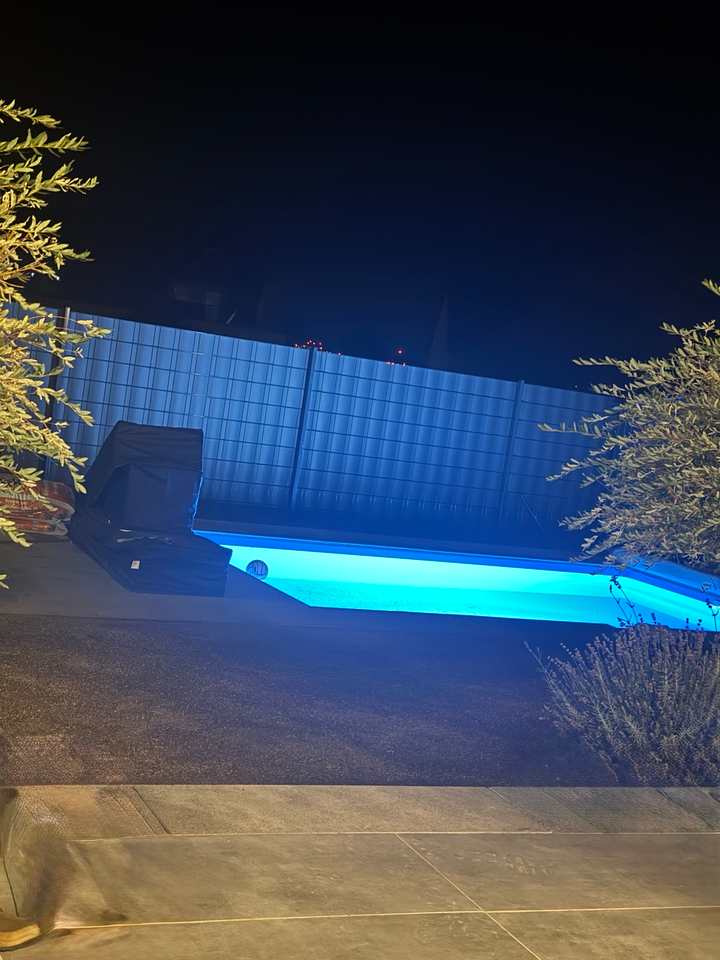 Fertiggestellter und beleuchteter Pool mit gepflasterter Umrandung in Calden bei Nacht