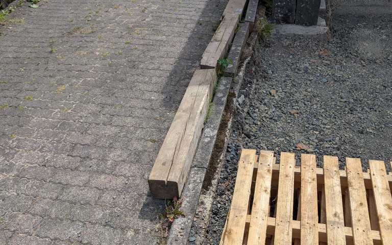 Beschädigte Bordsteine entlang einer Einfahrt vor Beginn der Sanierung
