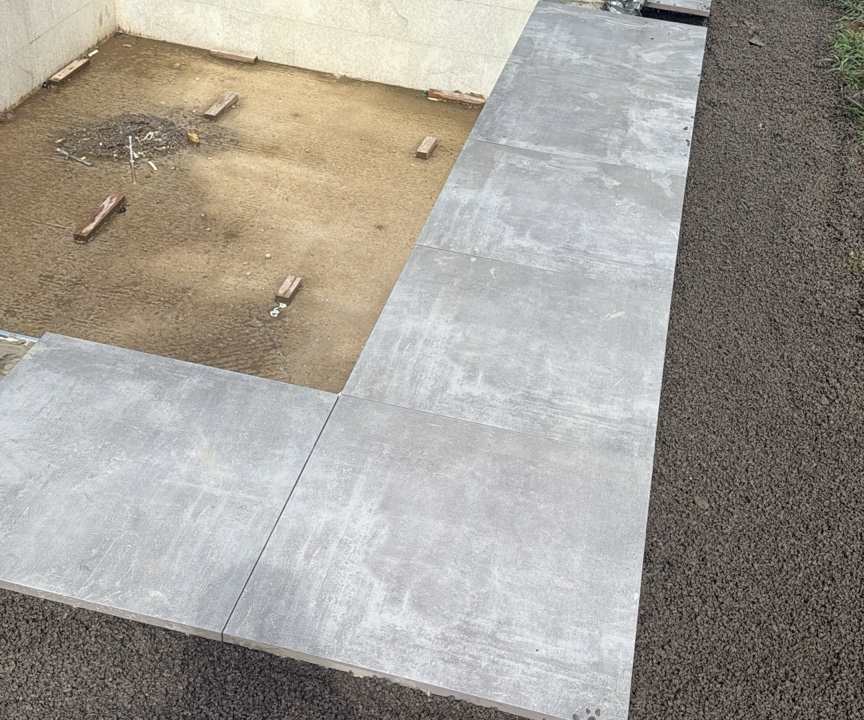 Poolrohbau mit fertig verlegten grauen Beckenrandplatten und vorbereitetem Unterbau