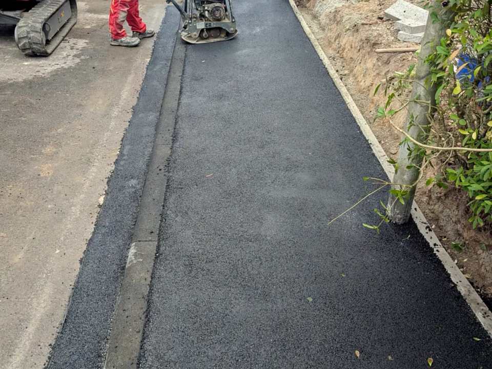 Verdichtung der Asphaltdeckschicht mit Rüttelplatte nach der Bordsteinabsenkung in Kassel