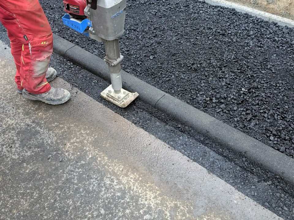 Saubere Fugenausbildung: Asphalt entlang der Bordsteinkante wird mit dem Stampfer verdichtet