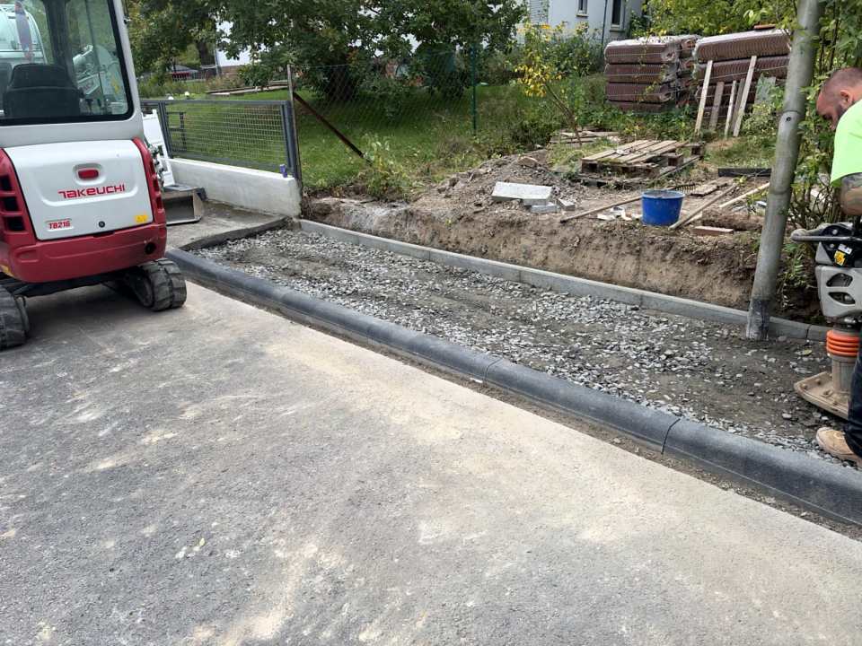 Gesetzte Bordsteine und Schottertragschicht vor dem Verdichten, Minibagger Takeuchi im Einsatz