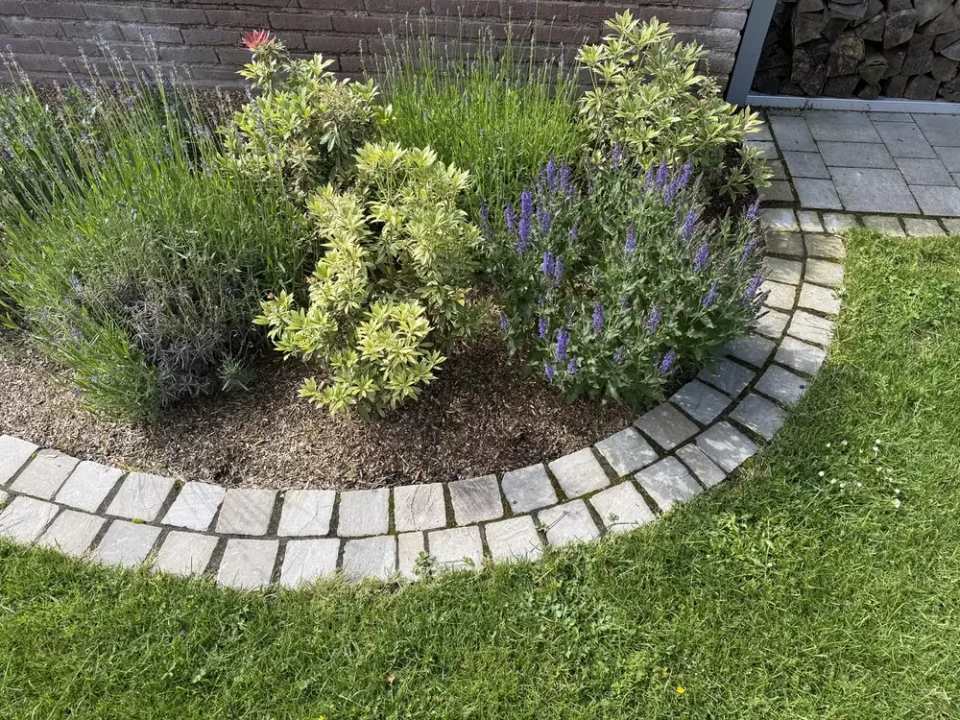 Hochwertige bepflanzte Beete mit Natursteinpflaster und Rasenfläche