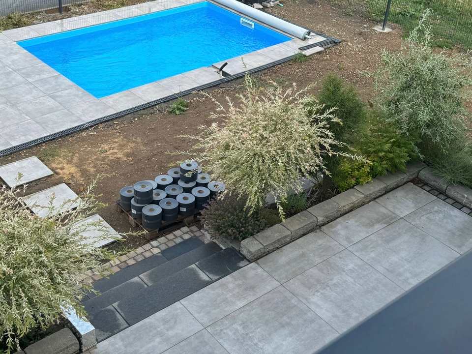 Fertiggestellter Pool mit grauer Beckenumrandung und angrenzender Außenanlage in Calden