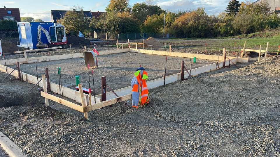 Große rechteckige Schalung mit vorbereitetem Schotterunterbau, Rohrdurchführungen und Absteckungen auf einer Baustelle