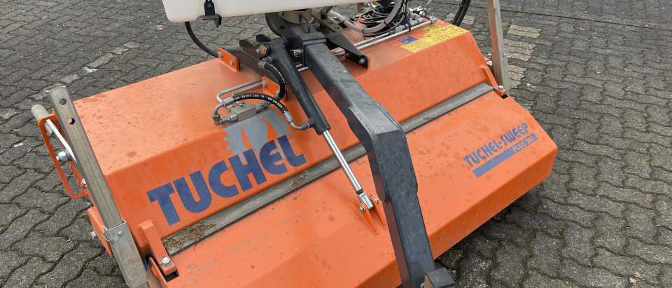 Orangefarbene hydraulische Kehrmaschine mit Wassertank auf einer gepflasterten Hoffläche